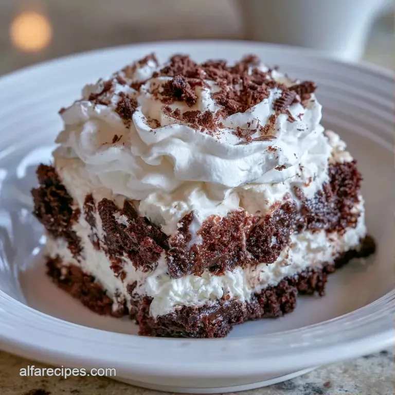 A neat slice of layered creamy dessert on a white plate, topped with whipped cream and a whole chocolate cookie.