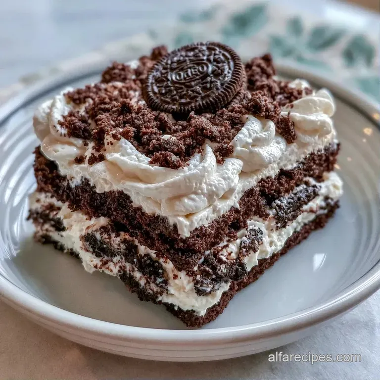 A square slice of layered cream and cookie cake topped with a swirl of whipped cream and a whole chocolate wafer.
