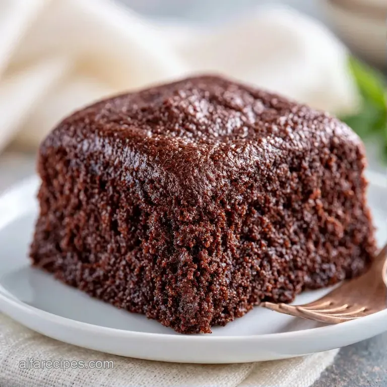 A neat square slice of moist yellow cake with thick white frosting on a white ceramic plate with a silver fork